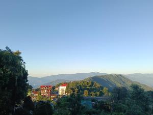 un pueblo en una colina con montañas al fondo en Hridhaan Hometay, en Kalimpong