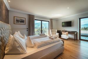 een slaapkamer met een bed, een bureau en een raam bij Historic Hotel Alte Goste in Valdaora