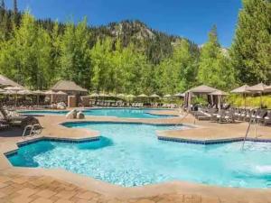 a pool at a resort with chairs and umbrellas at Remodeled Second Floor Valley View suite no resort fee in Olympic Valley
