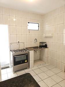 a kitchen with a stove and a sink at Casa com ar-condicionado no centro da cidade, bem localizada, 10min da praia a pé in Prado +2 photos
