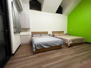 two beds in a room with green walls and wooden floors at 哈娜家Villa 