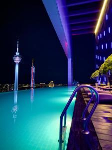ein Schwimmbad in der Nacht mit einem Turm im Hintergrund in der Unterkunft Crown Suites At Platinum KLCC in Kuala Lumpur