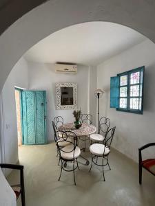 ein Esszimmer mit einem Tisch und Stühlen und einer blauen Tür in der Unterkunft Dar Temna Renovated traditional house in Erriadh