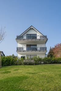 NickenichFerienwohnungen Pellenzblick - Wohnen auf Zeit -的一栋白色建筑，前面有一张长椅