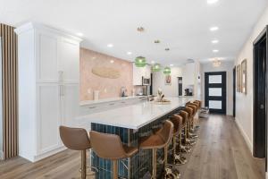 a kitchen with a long bar with brown chairs at Lux 6br5ba, Htd Pool, Hot Tub, Game Rm Sleeps 22 in West Bradenton