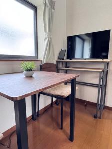 a wooden table with a television and a table and chair at FukuStay CCB1-201 福居 地下鉄駅徒歩2分 in Fukuoka