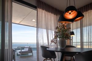 ein Esszimmer mit einem Tisch und einem großen Fenster in der Unterkunft Droomsuites Egmond aan Zee 4 personen by Droomvilla in Egmond aan Zee + 9 Fotos