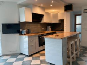 a kitchen with white cabinets and a wooden counter top at Charmante maison à 200m de la plage in Hossegor +25 photos