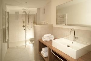 a white bathroom with a sink and a shower at Hotel Fil Da Mont in Selva di Val Gardena +37 photos