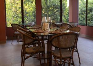 a dining room with a table and chairs and windows at Irroi Kaziranga in Kāziranga
