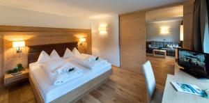 a bedroom with a bed and a desk with a television at Hotel Fil Da Mont in Selva di Val Gardena
