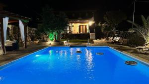 a blue swimming pool in front of a house at night at Cittadella Asprovalta 3BR - private pool in Asprovalta