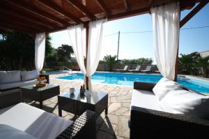 a patio with a couch and chairs and a pool at Cittadella Asprovalta 3BR - private pool in Asprovalta +44 photos