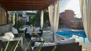 a patio with white furniture and a swimming pool at Cittadella Asprovalta 3BR - private pool in Asprovalta