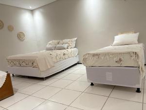 a white bedroom with two beds in a room at Pousada Casa de Geralda in Altaneira +4 photos