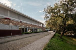 a building with a tree next to a sidewalk at Axis Ponte de Lima Golf Resort Hotel in Ponte de Lima