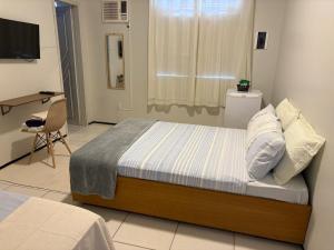 a bedroom with a bed and a desk and a television at Pousada Casa de Geralda in Altaneira