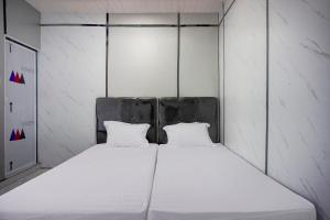 een bed met twee witte kussens in een kamer bij OYO 94903 Akasia Guesthouse in Perbaungan +18 foto's