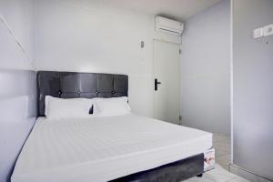een slaapkamer met een wit bed met een zwart hoofdeinde bij OYO 94903 Akasia Guesthouse in Perbaungan