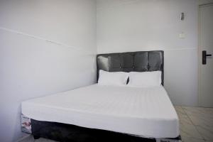 een wit bed met een zwart hoofdeinde in een kamer bij OYO 94903 Akasia Guesthouse in Perbaungan