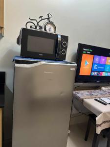 a microwave and a computer on top of a refrigerator at Shell Residences Staycation in Sampong +1 photo