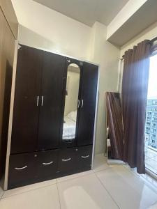 a black cabinet with a mirror in a room at Shell Residences Staycation in Sampong