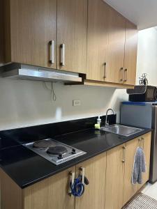 a kitchen with a black counter top and a sink at Shell Residences Staycation in Sampong