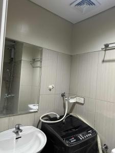 a bathroom with a sink and a toilet and a mirror at Shell Residences Staycation in Sampong