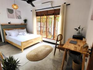 a bedroom with a bed and a table and a window at Kalavida - 2 Mins walk to Kabalana Beach in Piyadigama