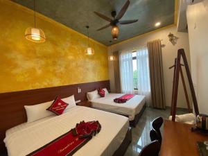 a bedroom with two beds and a ceiling fan at Tam Coc HaVi's Hotel - Restaurant in Văn Lâm