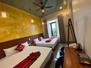 a hotel room with two beds and a table at Tam Coc HaVi's Hotel - Restaurant in Văn Lâm +10 photos