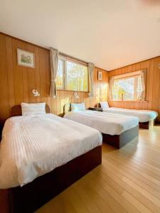 two beds in a room with wooden walls at The lakeview toya Shirokumanoyado in Lake Toya