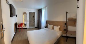 a bedroom with a white bed and a red chair at B&B HOTEL Thionville Yutz Route du Luxembourg in Basse-Yutz +23 photos