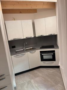 a kitchen with white cabinets and a sink at Appartamento Ambro in Tione di Trento