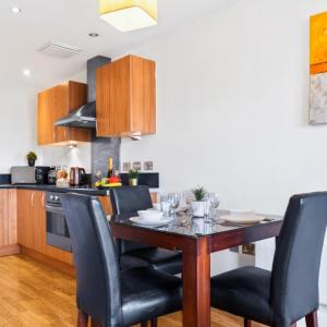 una cucina con un tavolo di legno e sedie nere di Stylish Apartment - Private Parking - Balcony - Chinatown - 49Arc a Birmingham Altre 24 foto