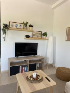 Una sala de estar con televisión y una mesa de café. en Getaway with views of the rice fields Relax and beach, en Els Muntells