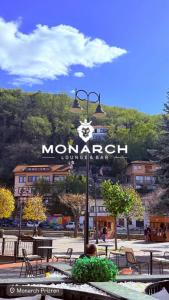 un hombre sentado en una mesa frente a una señal en Monarch Hotel, en Prizren