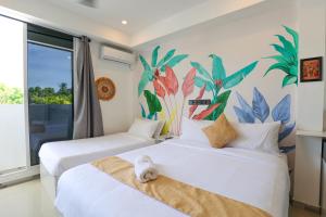 Dos camas en una habitación con un mural en la pared. en Sands Garden Hotel, en Thoddoo 88 fotos más