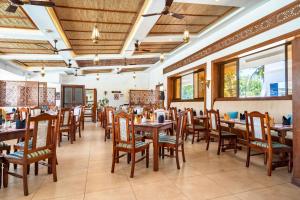 a restaurant with wooden tables and chairs and windows at PrideInn Hotel Diani in Diani Beach