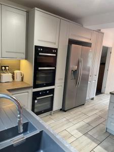 a kitchen with white cabinets and a stainless steel refrigerator at Cosy 3-bed Terrace Home, Nantwich in Nantwich +13 photos
