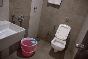 a bathroom with a sink and a toilet and a bucket at Hotel Royal Residency in Umele