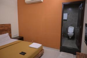 a bathroom with a bed and a toilet in it at Hotel Royal Residency in Umele