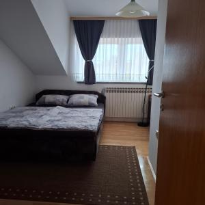 a small bedroom with a bed and a window at Apartman Anita in Varaždin