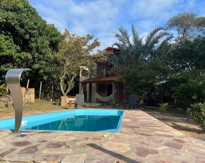 a villa with a swimming pool in front of a house at Recanto Pitanga in Vale do Capao