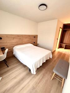 een slaapkamer met een wit bed en een stoel bij Avenida Gijón Centro in Gijón