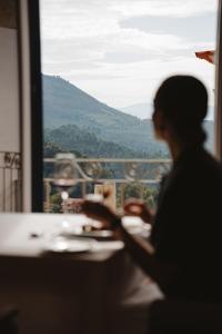una persona sentada en una mesa frente a una ventana en The Vinea Collection Hotel by Piamonte Hotels, en Monção
