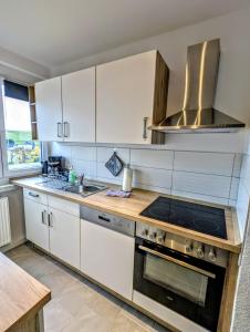 a kitchen with white cabinets and a stove top oven at Ferienwohnung August 29 in Gelenau