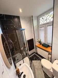 a bathroom with a sink and a toilet and a television at Zakątek Centrum 3 in Suwałki