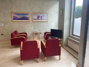 a waiting room with red chairs and a television at Avenida Gijón Centro in Gijón