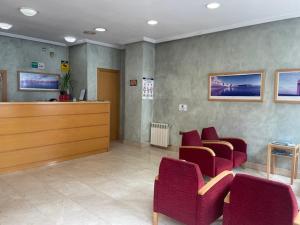 a waiting room with red chairs and a reception desk at Avenida Gijón Centro in Gijón +23 photos